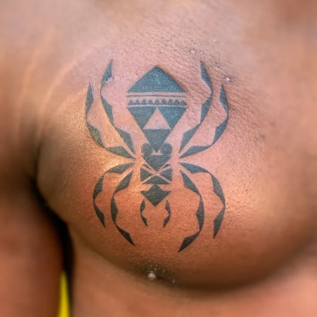 A tribal geometric symbol tattoo of a spider composed of triangles on the chest.