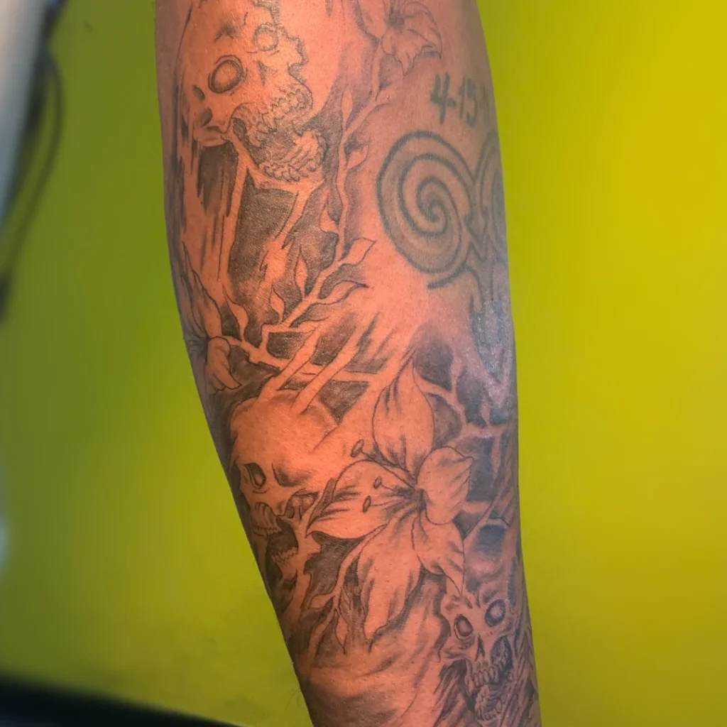 A series of skulls and cherry blossoms as filler between pre-existing tattoos, rendered in black and grey.