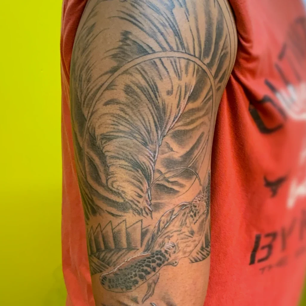 Upper arm tattoo of a whirlpool with a sea turtle swimming into the foreground.